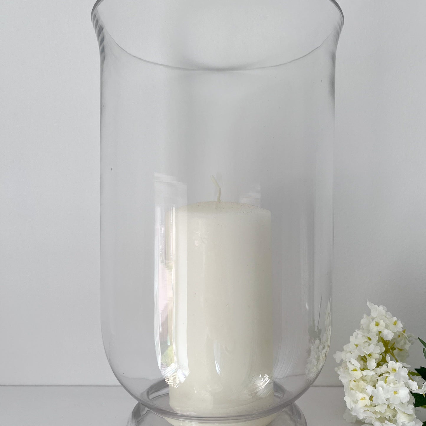 clear glass tall hurricane vase holding a tall pillar candle