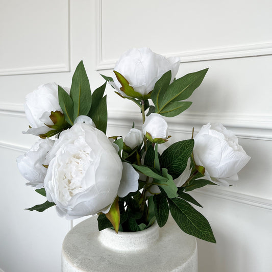 an arrangement of white faux peonies displayed in a large vase