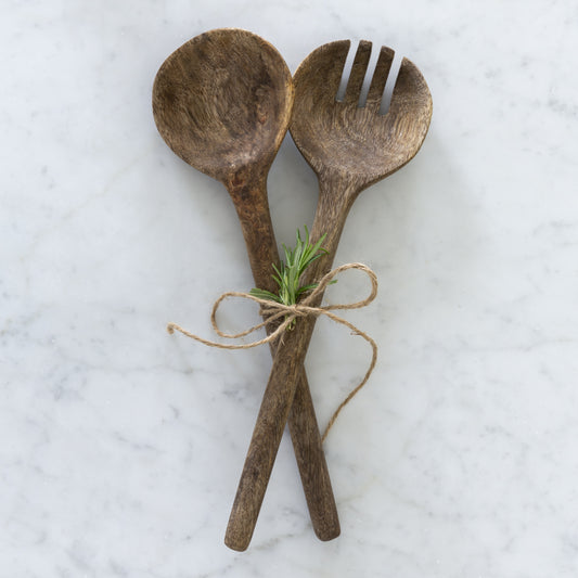 a set of mango wood salad servers tied together with yarn and a sprig of rosemary