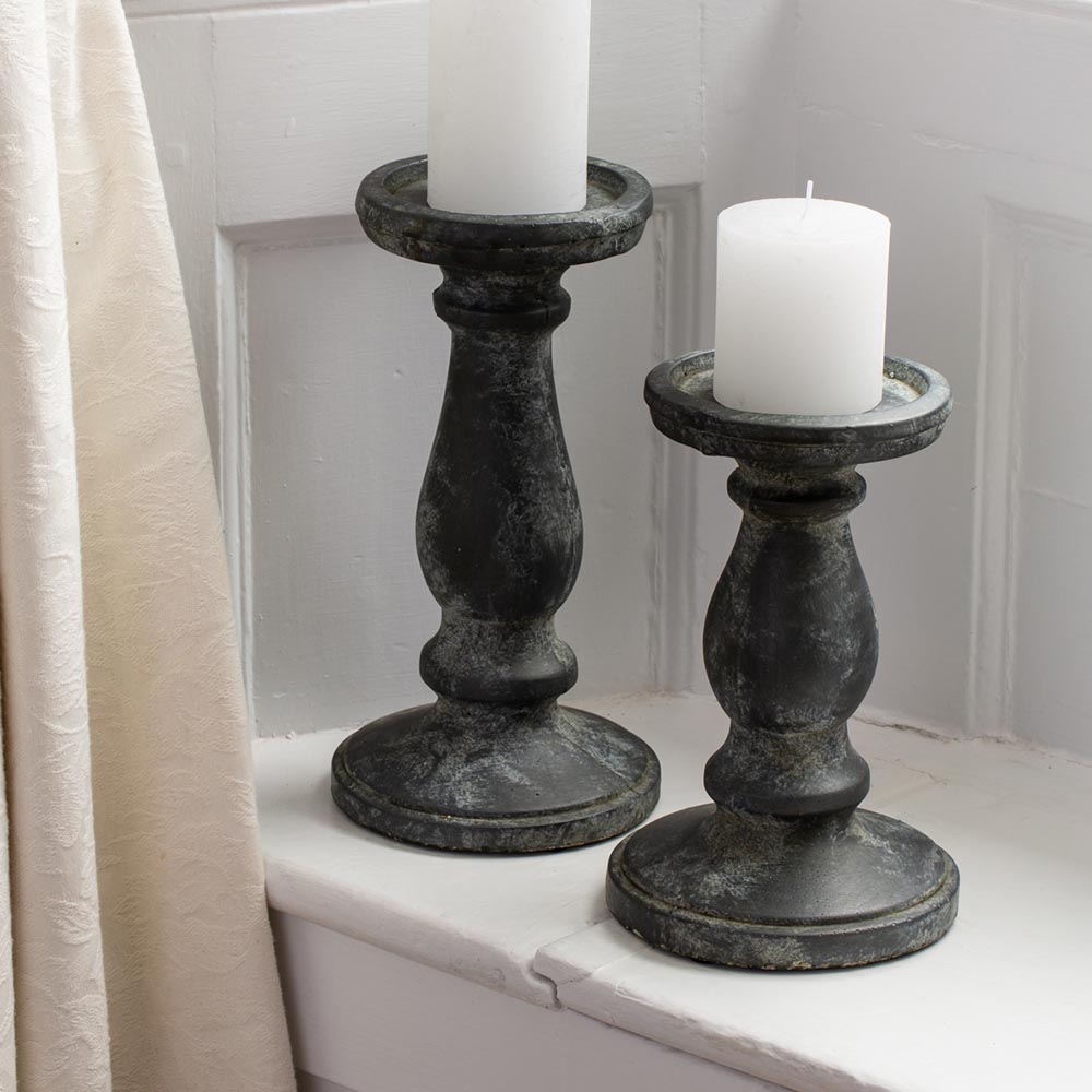 two sizes of chunky dark grey rustic-looking candlesticks, styled with varying sizes of pillar candles