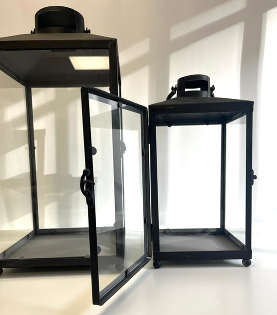 Three black lanterns with glass panels on a white background