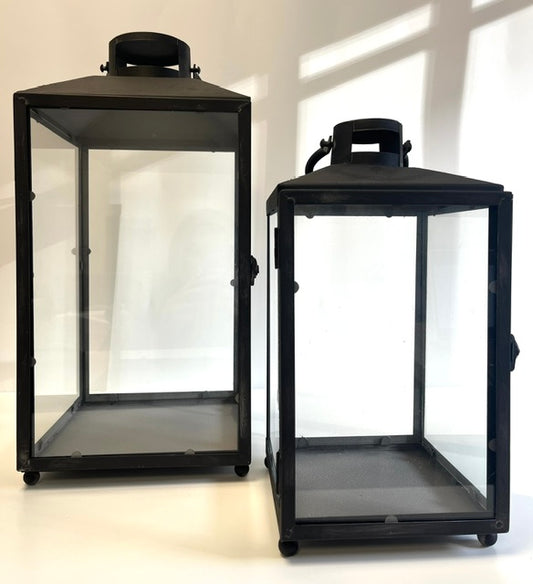 Two black lanterns with glass panels on a white background