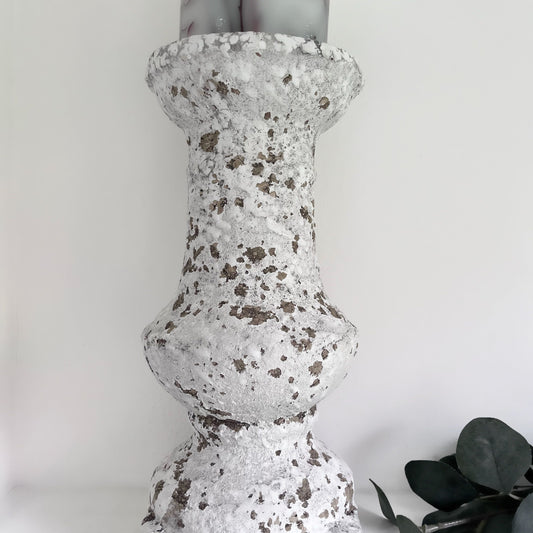 distressed stone effect chunky candlestick holding a botanical candle