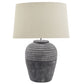 close up view of large grey carved stone lamp with linen shade