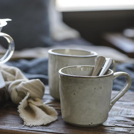 two rustic mugs in the shade sand, sitting on a wooden chopping board