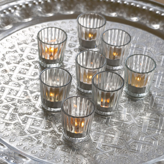 a display of 8 clear glass ribbed votives holding lit tealights